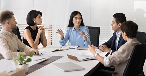 Conference room with five people sitting in chairs having a discussion
