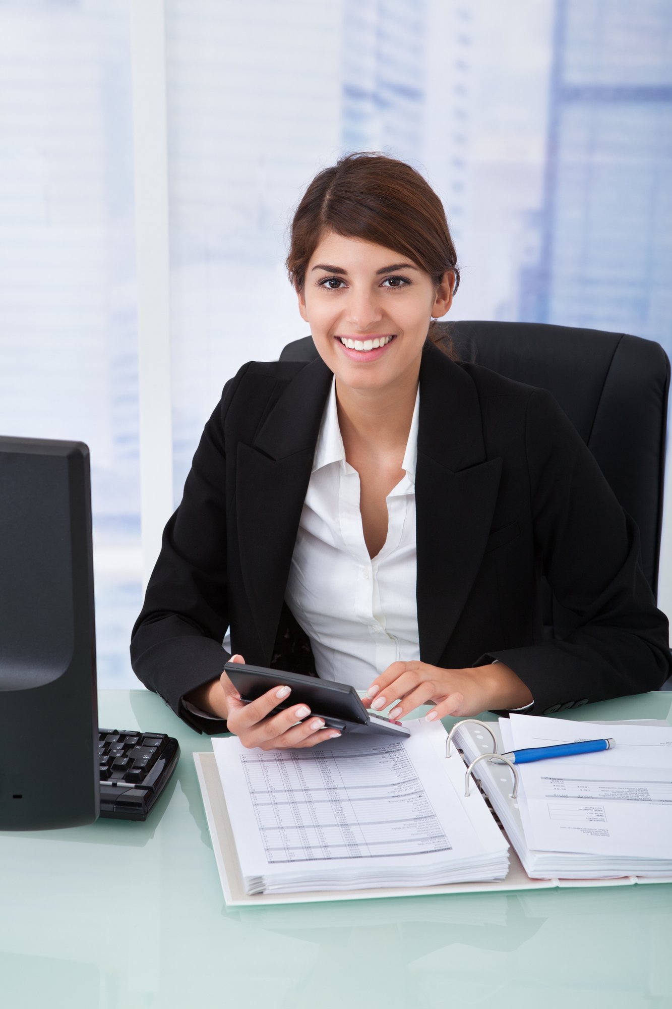 Confident-Businesswoman-Using-Calculator-At-Office-Desk-513824589_1415x2122