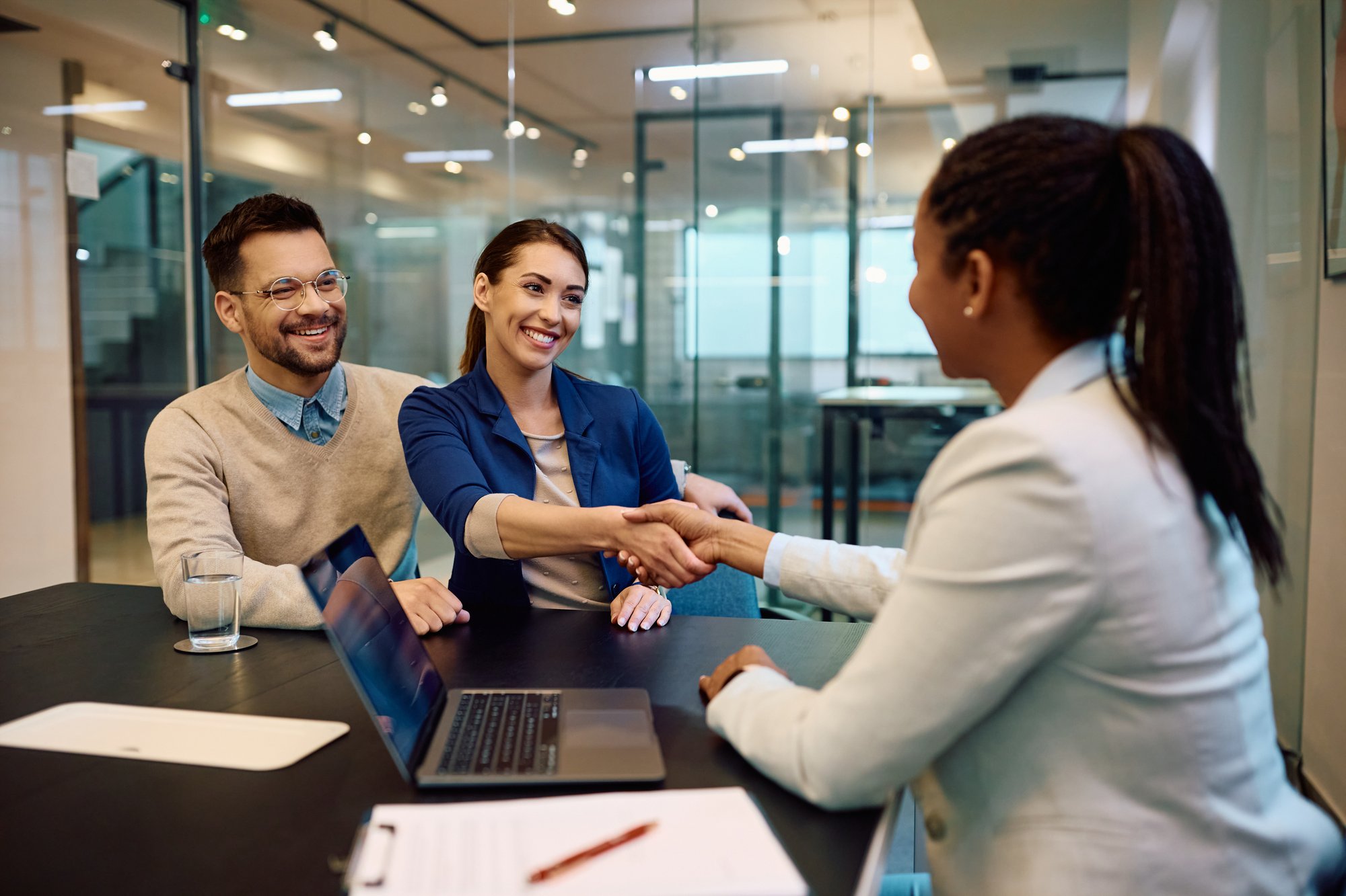 Happy-couple-greeting-their-financial-advisor-in-the-office.-1490898201_3869x2579