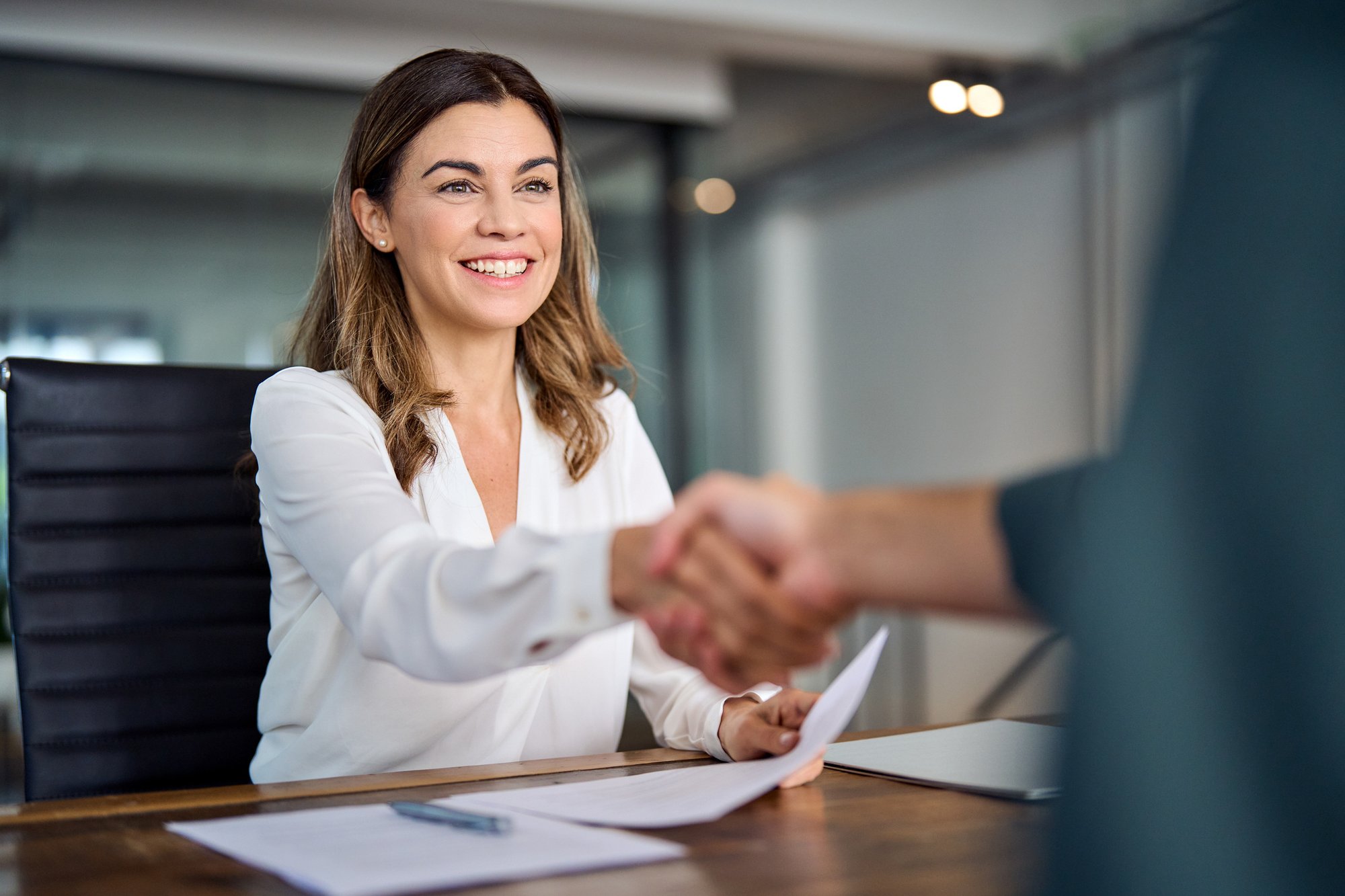Happy-mid-aged-business-woman-manager-handshaking-at-office-meeting.-2004890520_2124x1416