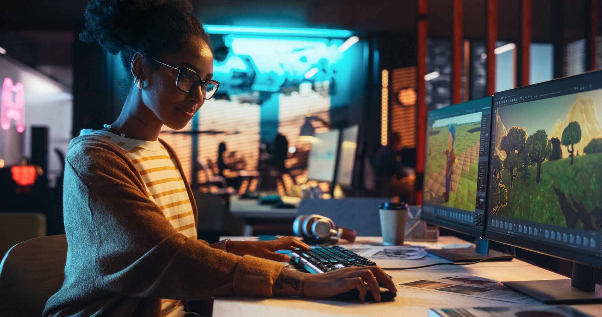 Portrait-of-Female-Video-Game-Designer-Working-on-a-New-3D-Level-on-Desktop-Computer-in-Creative-Office.-Black-Focused-Woman-Creating-Metaverse-and-Adding-Details-to-a-Game-Environment-2150307505_2388x1259