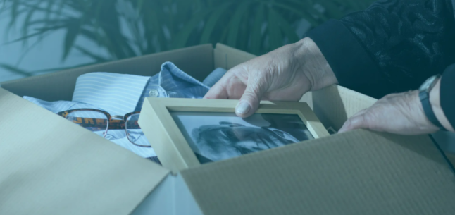 old woman looking at picture of old man in box