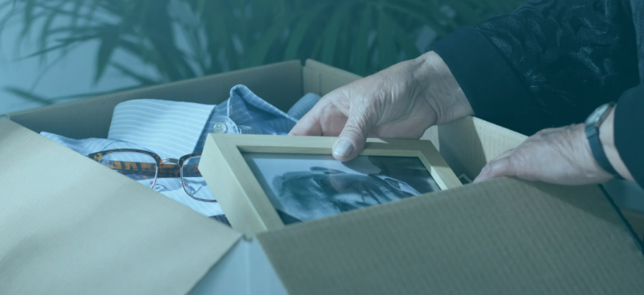 old woman looking at picture of old man in box