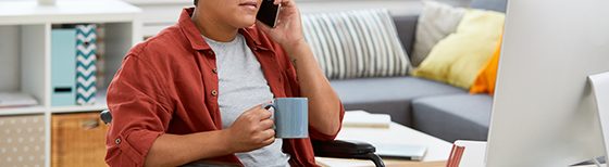 person in wheelchair holding mug and talking on cellphone