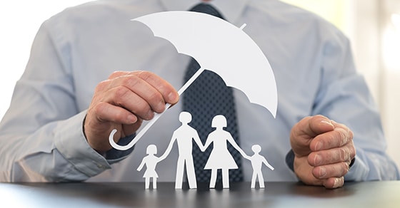 man holding paper umbrella over paper family