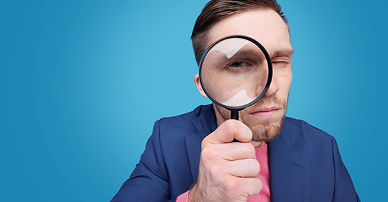 man looking into magnifying glass