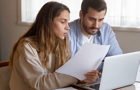 married couple looking at laptop and paper