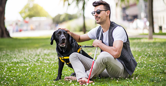 blind man sitting with service dog in park