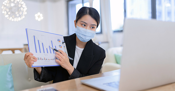 woman wearing mask showing graph to laptop