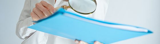 woman holding magnifying glass over blue folder