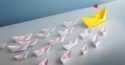 small pink paper boats following large yellow paper boat