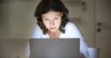 woman wearing white looking at laptop