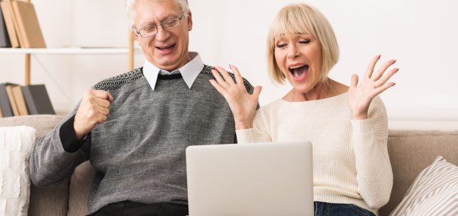 excited older couple looking at laptop